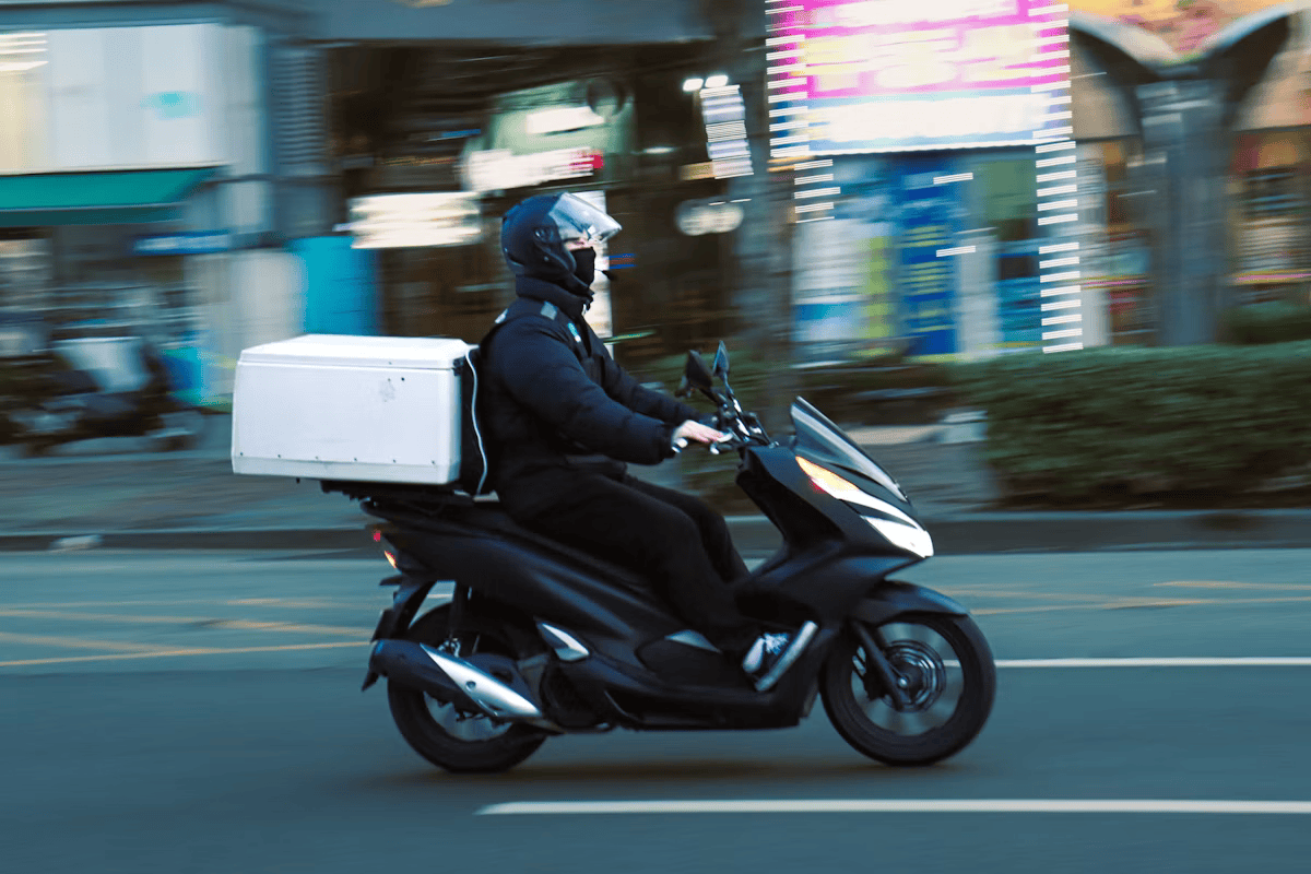 A delivery rider on a scooter carrying an order box within a service zone